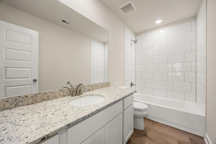 A sleek full bathroom showcasing a dual-sink vanity with granite countertops, ample storage, and a clean, modern design with a combination tub and shower. A sleek full bathroom showcasing a dual-sink vanity with granite countertops, ample storage, and a clean, modern design with a combination tub and shower.