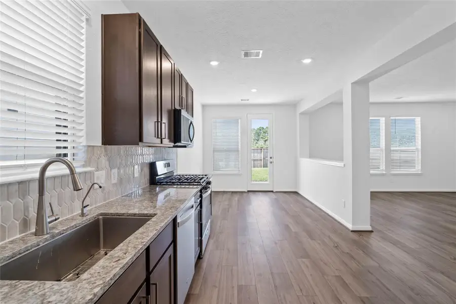 An open-concept kitchen provides a clear view into the adjacent dining nook, creating a cohesive space for cooking and gathering. The kitchen is also equipped with a self-rimming single-bowl sink and a contemporary Moen faucet. An open-concept kitchen provides a clear view into the adjacent dining nook, creating a cohesive space for cooking and gathering. The kitchen is also equipped with a self-rimming single-bowl sink and a contemporary Moen faucet.