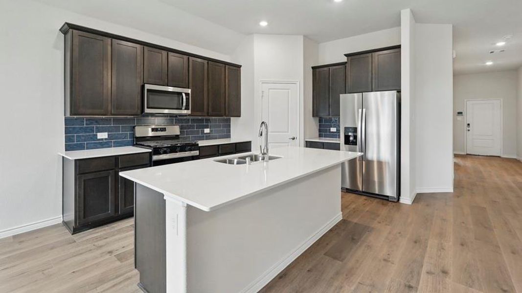 Modern kitchen featuring a central island with an undermount sink and gooseneck faucet