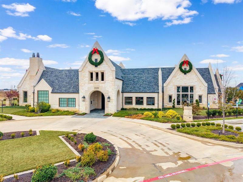View of front of home with stone siding, a front yard, and curved driveway