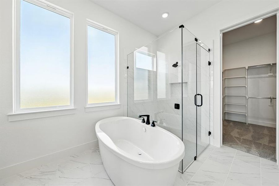 Full bathroom with light marble finish floors, a soaking tub, a stall shower, a walk in closet, and recessed lighting
