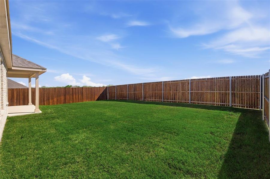 Expansive green lawn with a full privacy fence