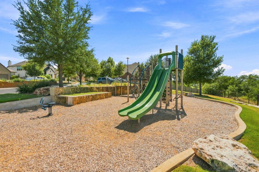An inviting community playground features a modern play structure nestled among mature trees.