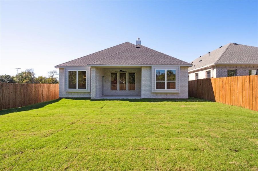 Rear view of property featuring a yard, ceiling fan, and a patio area