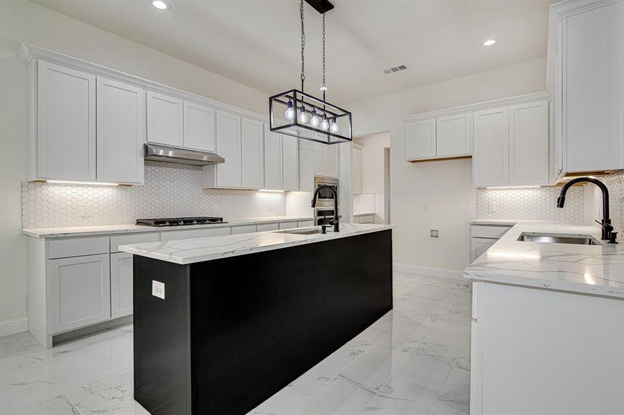 Kitchen with white cabinets, sink, ventilation hood, and a kitchen island with sink