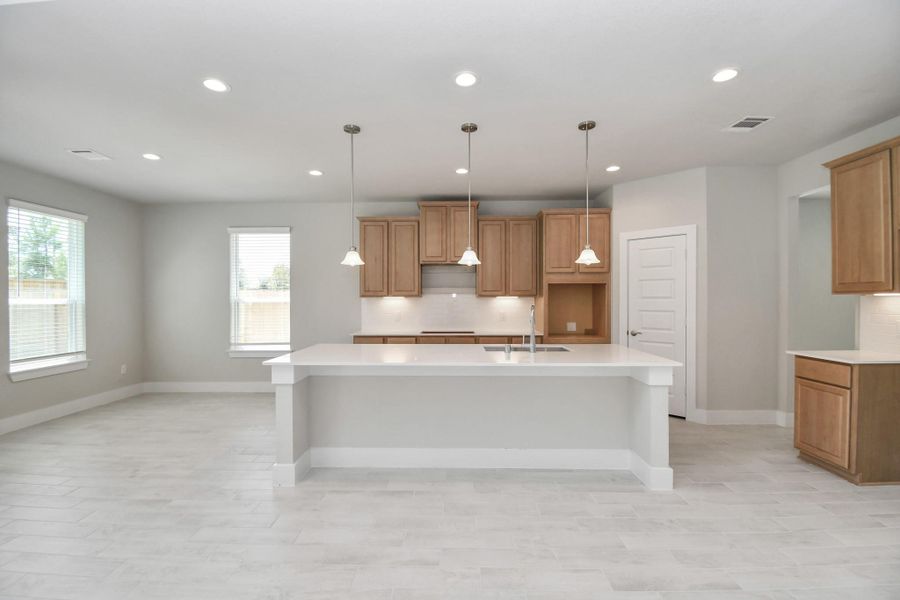 The kitchen is a culinary haven, featuring granite countertops, a tile backsplash, stainless steel appliances, 42” upper cabinets, and undercabinet lighting. Sample photo of completed home with similar floor plan. Actual colors and selections may vary.