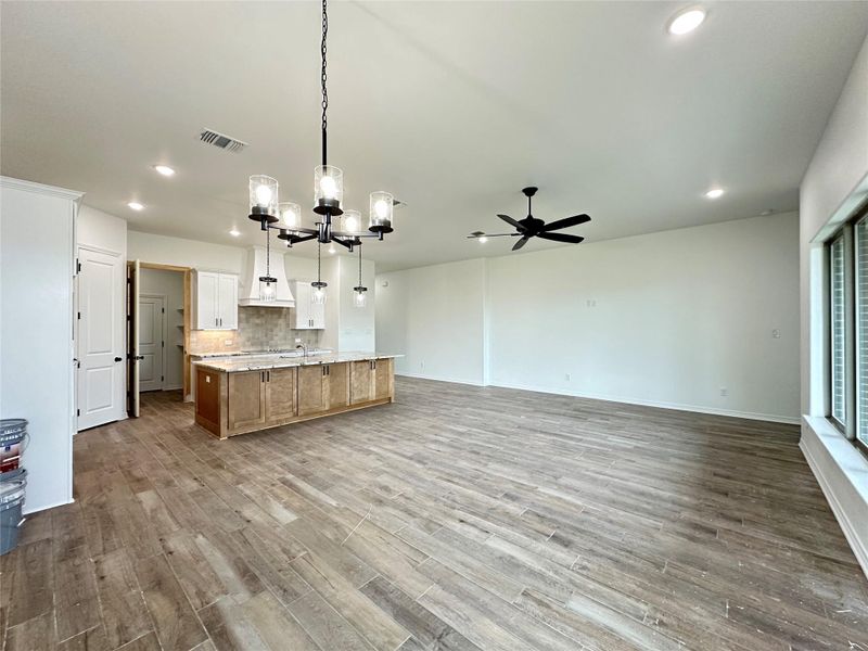 Kitchen featuring a chandelier, open floor plan, hanging light fixtures, white cabinetry, and a spacious island