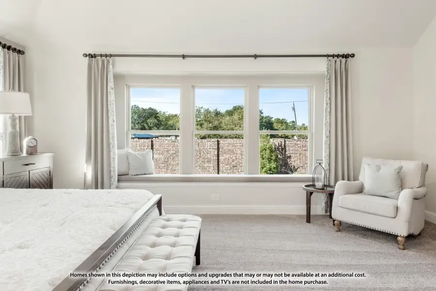 Bedroom with large triple window, built-in window seat, neutral carpet, and sitting area with armchair