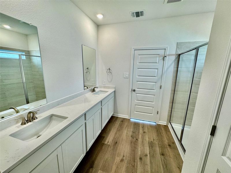 Bathroom featuring wood finished floors, double vanity, a shower stall, and recessed lighting Bathroom featuring wood finished floors, double vanity, a shower stall, and recessed lighting