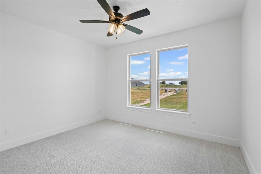 Unfurnished room with light colored carpet and ceiling fan Unfurnished room with light colored carpet and ceiling fan