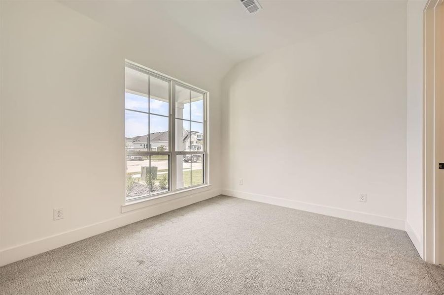 Empty room with carpet flooring, baseboards, and vaulted ceiling