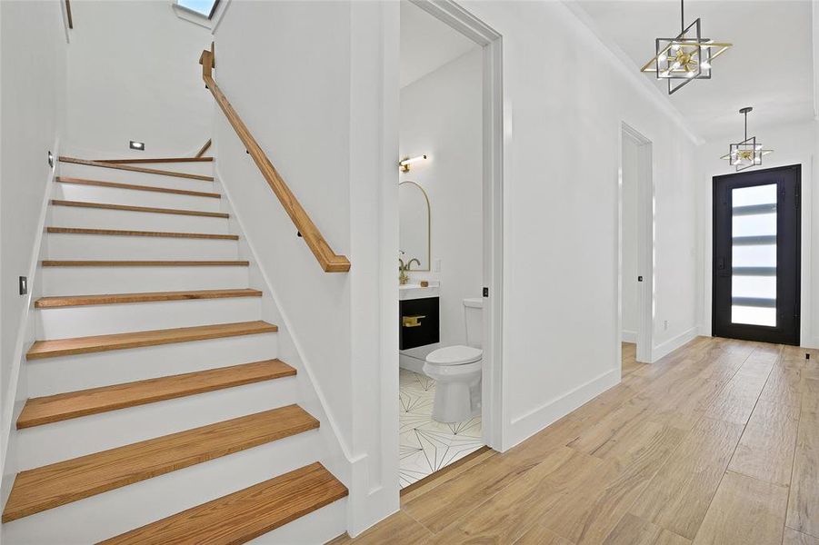Foyer featuring stairway, a chandelier, light wood-style flooring, and baseboards