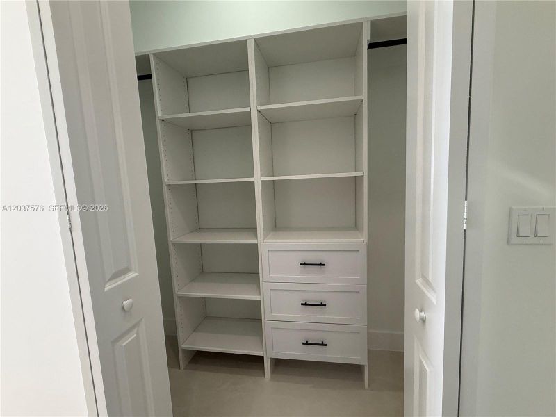 Custom closet system with white shelving, integrated drawers, and matte black hardware