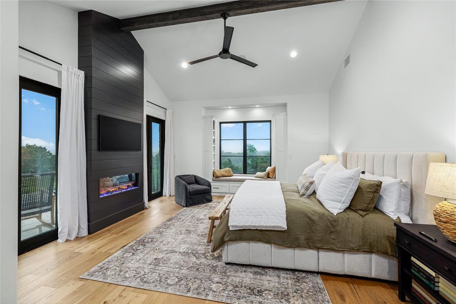 Bedroom with beamed ceiling, a fireplace, access to exterior, and light hardwood / wood-style floors