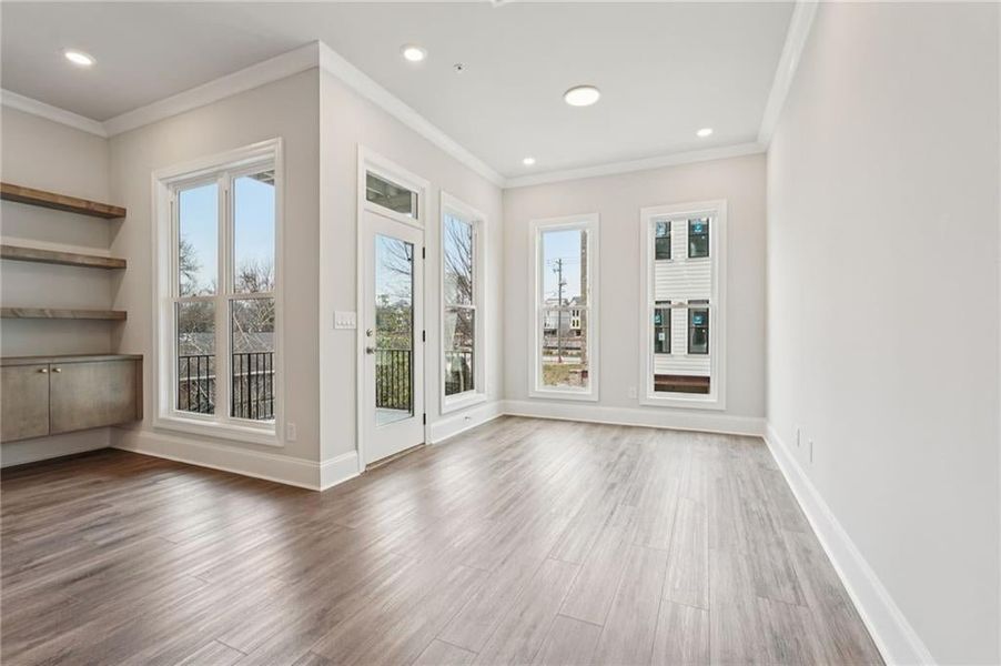 Spare room featuring plenty of natural light, light wood finished floors, ornamental molding, and recessed lighting