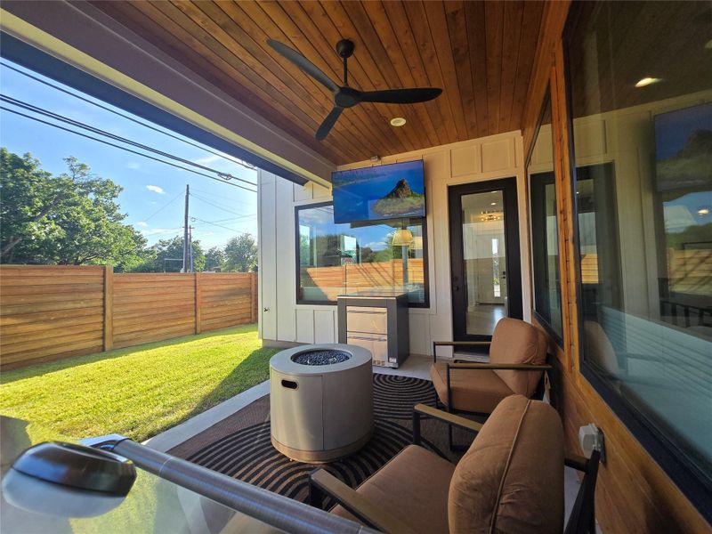 Rich wood plank ceilings shelter a concrete patio transitioning directly to a grassy yard.
