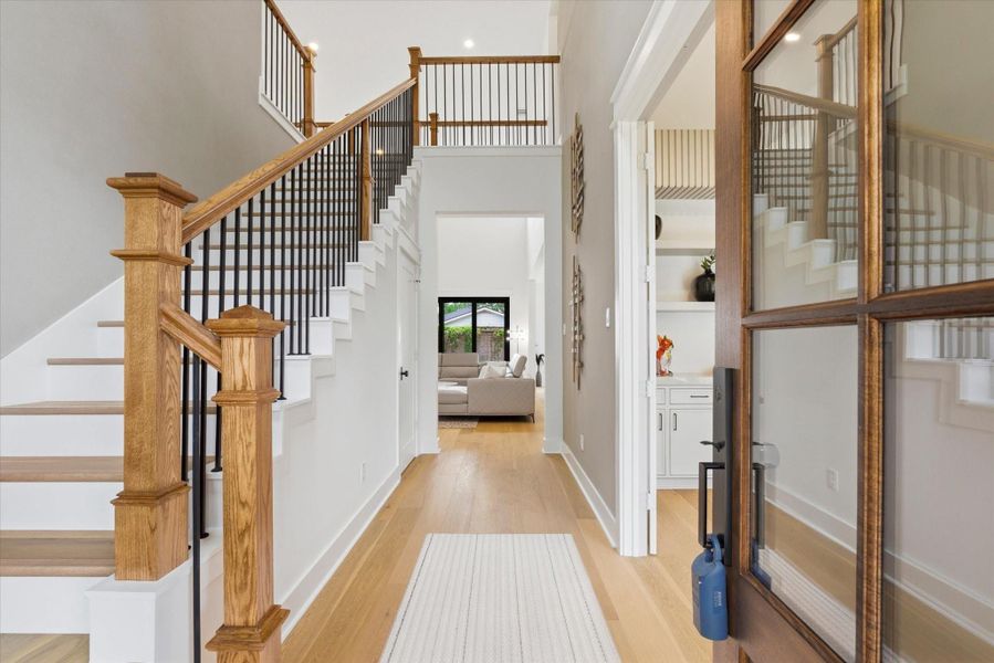 As you enter, you’re welcomed by 21-foot ceilings in the foyer and striking stucco-finished walls that create an immediate wow factor. To the left, the elegant staircase features beautiful wood flooring, and to the right, an impressive office space.