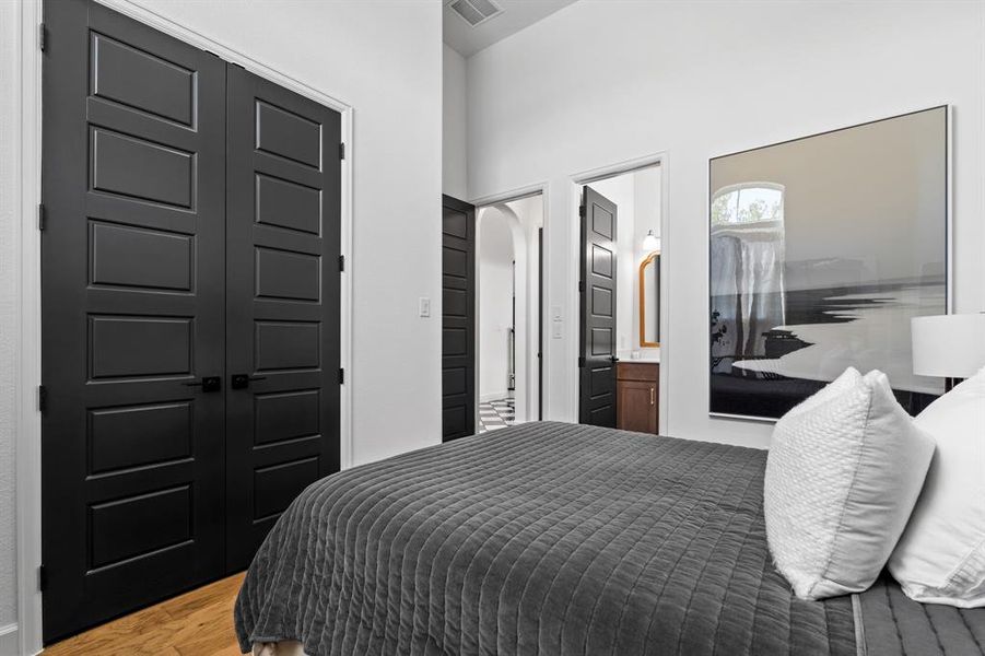 Bedroom featuring light wood-style floors, a closet, arched walkways, and connected bathroom Bedroom featuring light wood-style floors, a closet, arched walkways, and connected bathroom