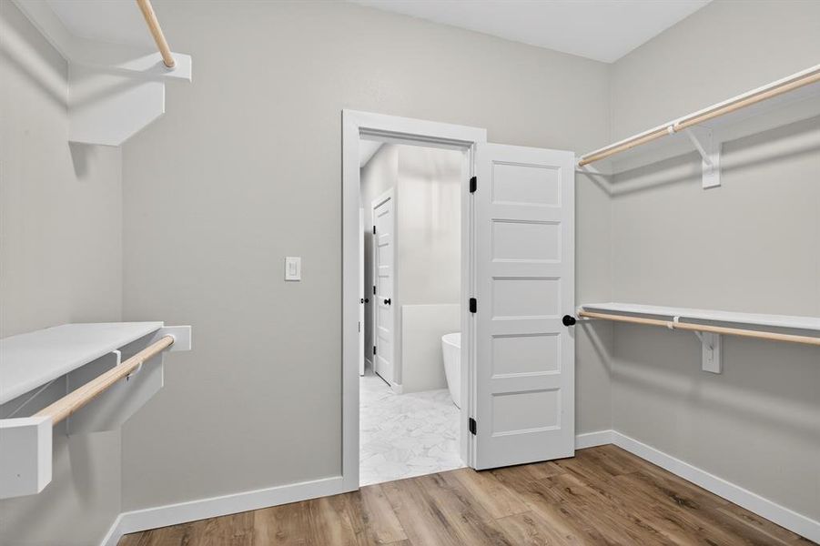 Primary closet features shelving and rods and connects to the primary bathroom but can be closed off.