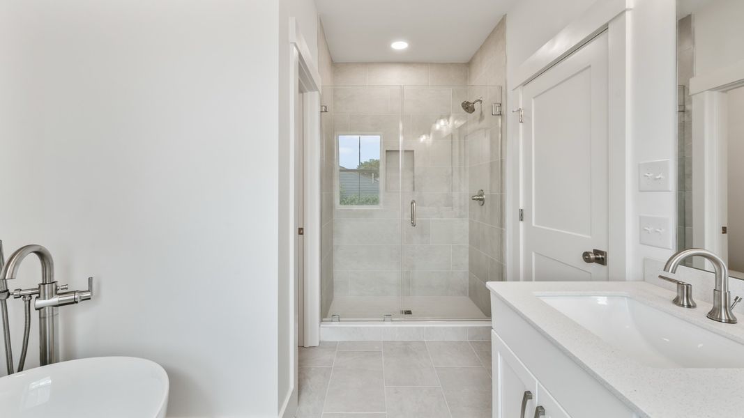 Spacious primary bathroom in the Sullivan home plan featuring dual vanities, a walk-in shower, and elegant details.