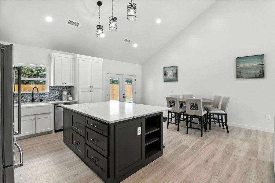 Kitchen with a center island, french doors, open shelves, white cabinets, and high vaulted ceiling