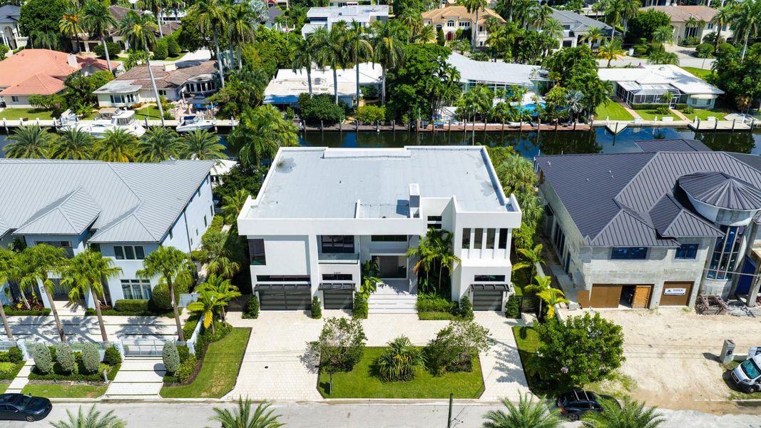 A direct overhead shot of a modern white residence with sleek architecture, set along the canal with tropical landscaping. A direct overhead shot of a modern white residence with sleek architecture, set along the canal with tropical landscaping.