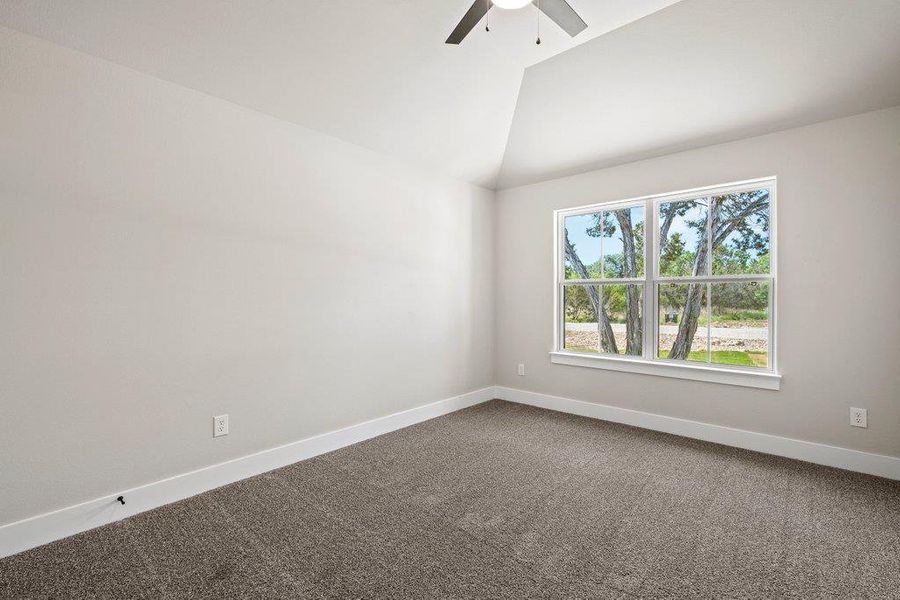 Unfurnished room with a ceiling fan, baseboards, dark carpet, and lofted ceiling Unfurnished room with a ceiling fan, baseboards, dark carpet, and lofted ceiling