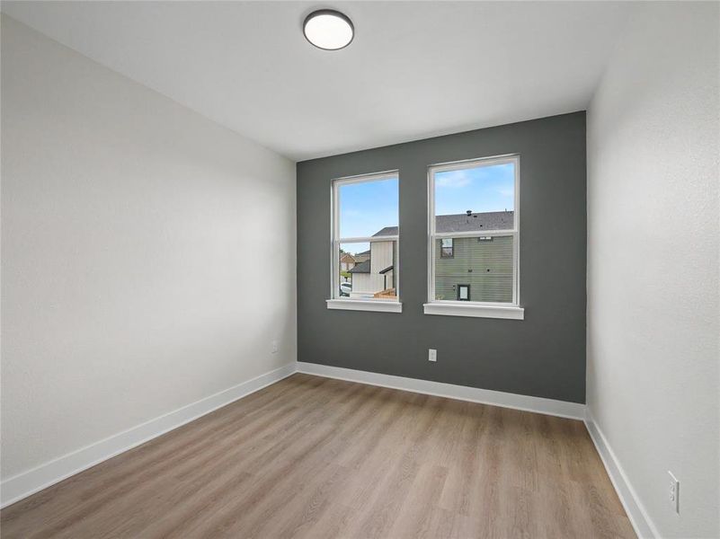 Room featuring wood-finish flooring, white baseboards, and a contemporary flush-mount ceiling light
