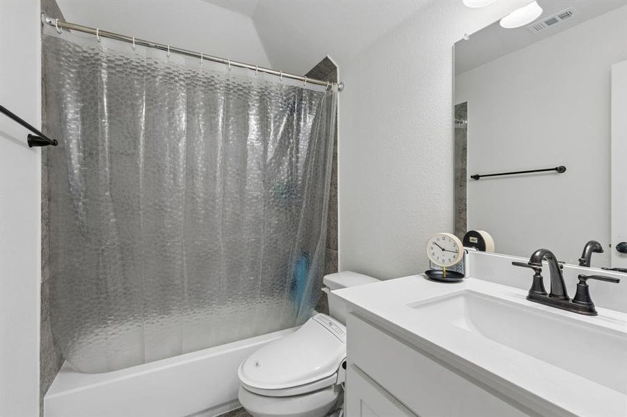 Bathroom featuring a white vanity with an integrated sink, dark bronze-finish hardware, and a framed mirror