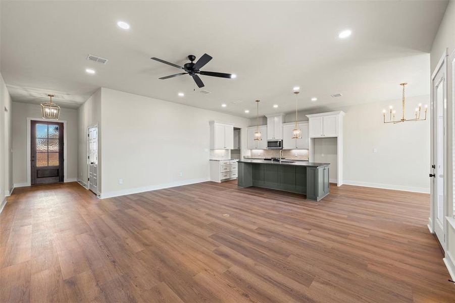 Unfurnished living room with a chandelier, dark wood-style floors, a ceiling fan, and recessed lighting