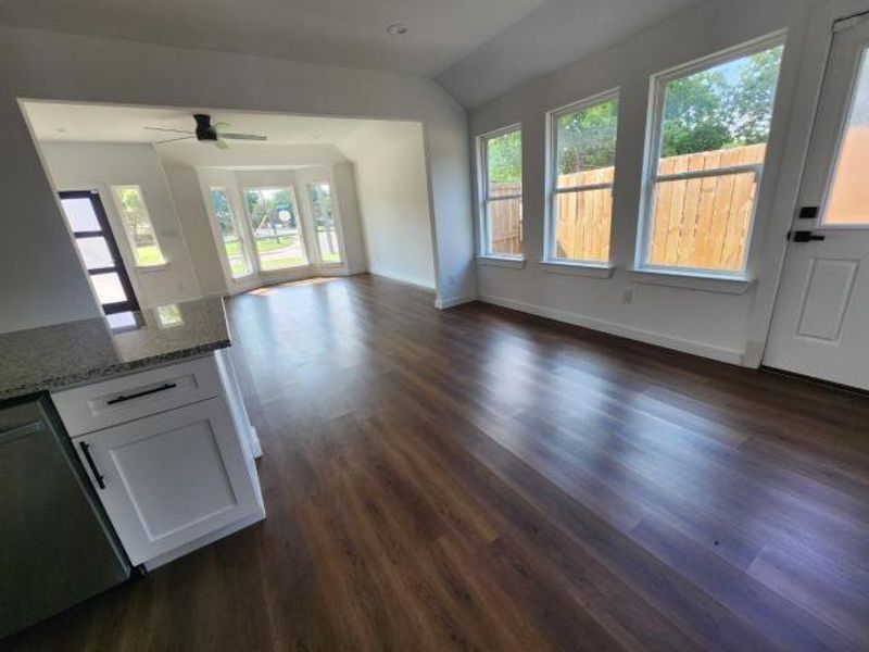 Unfurnished living room featuring dark wood-style flooring, ceiling fan, and vaulted ceiling Unfurnished living room featuring dark wood-style flooring, ceiling fan, and vaulted ceiling