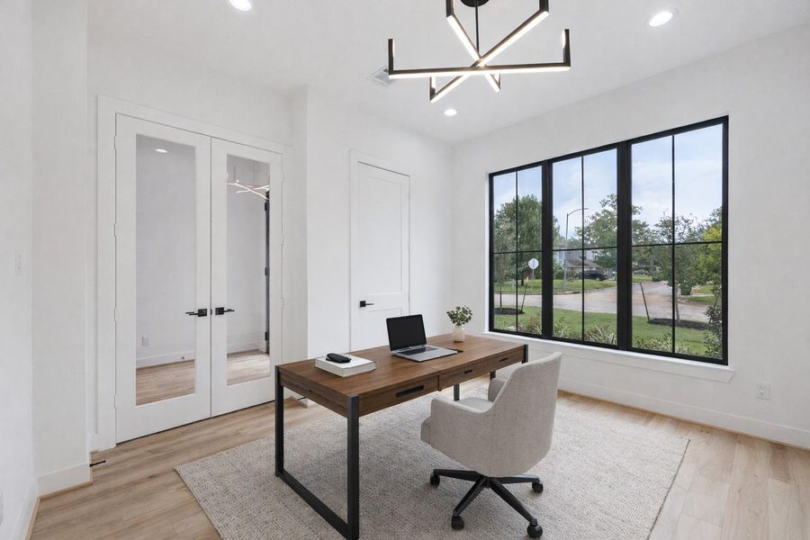 Framed glass doors open into a light-filled office, where bold lighting and wide-plank floors elevate the space. Oversized windows provide a direct view of the front yard and neighborhood, creating an energizing setting for focus and creativity. *Virtually Staged* Framed glass doors open into a light-filled office, where bold lighting and wide-plank floors elevate the space. Oversized windows provide a direct view of the front yard and neighborhood, creating an energizing setting for focus and creativity. *Virtually Staged*