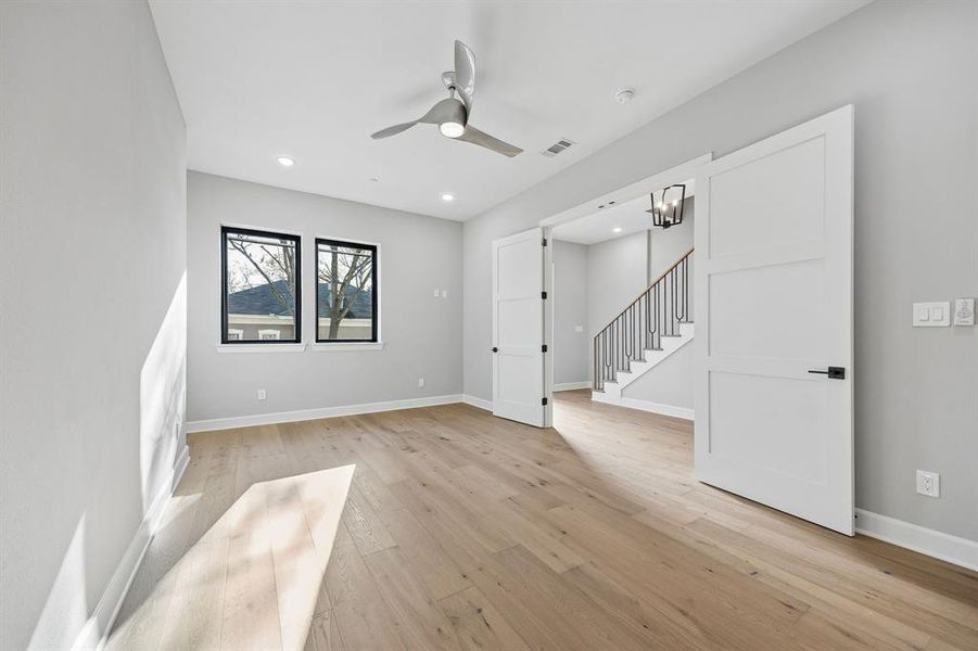 Empty room featuring light wood-type flooring, a ceiling fan, hanging lights, and a barn door Empty room featuring light wood-type flooring, a ceiling fan, hanging lights, and a barn door