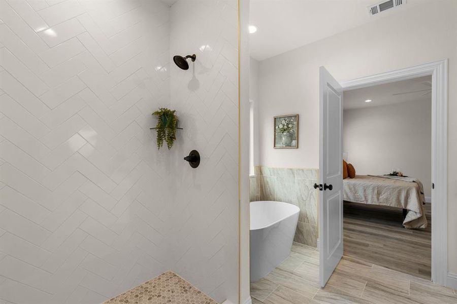 Bathroom featuring tile walls and shower with separate bathtub