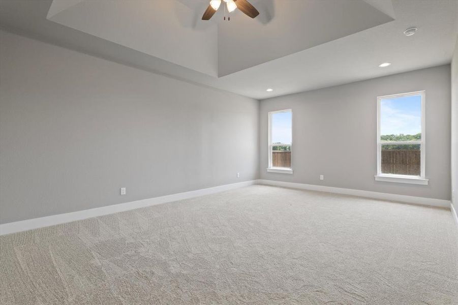 Carpeted spare room with ceiling fan and plenty of natural light