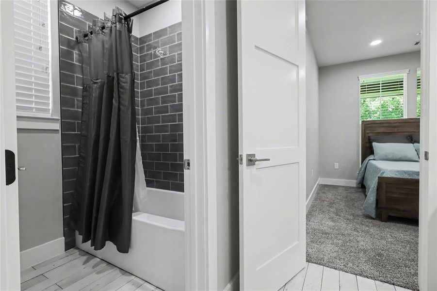 Bathroom featuring subway tile shower surround and light wood-finish flooring
