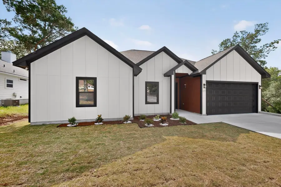 A modern farmhouse-style residence with striking black trim accents and a well-kept front lawn welcomes you home.