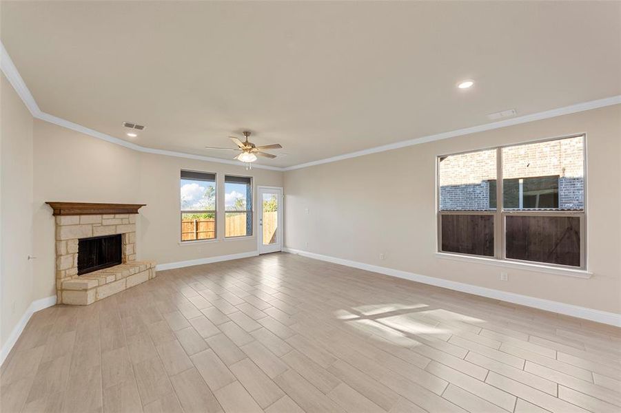 Unfurnished living room with a fireplace, ceiling fan, light wood-type flooring, and crown molding