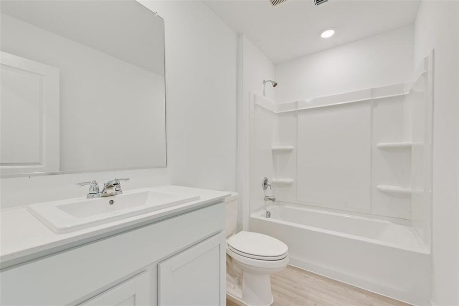 Full bathroom with vanity, toilet, shower / bath combination, and hardwood / wood-style floors