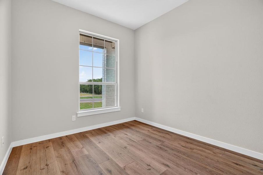 Spacious room featuring wood-finish flooring, light gray wall paint, and white trim Spacious room featuring wood-finish flooring, light gray wall paint, and white trim