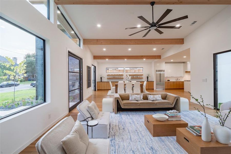 Living room with ceiling fan, light wood-type flooring, beam ceiling, and a towering ceiling