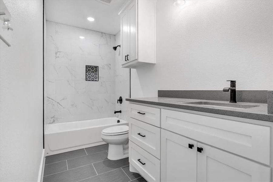 Full bathroom with toilet, tiled shower / bath, vanity, and tile floors