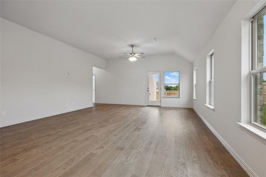 Unfurnished living room featuring wood finished floors, lofted ceiling, and a ceiling fan Unfurnished living room featuring wood finished floors, lofted ceiling, and a ceiling fan