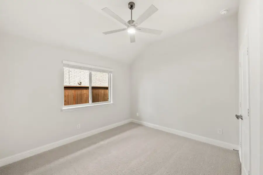 Empty bedroom with white walls, gray carpet, ceiling fan, and single window Empty bedroom with white walls, gray carpet, ceiling fan, and single window