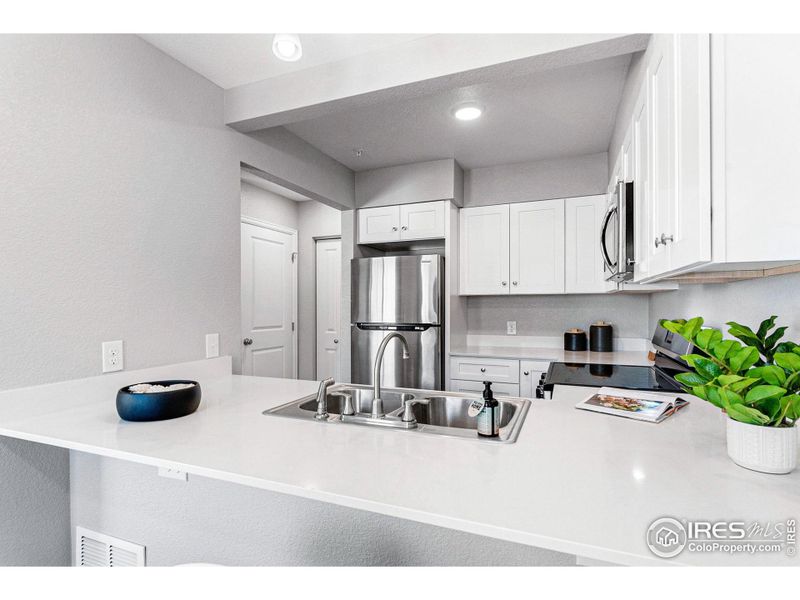 Brand new kitchen with modern white cabinets, quartz countertops and stainless appliances.