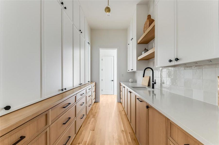 Kitchen with decorative backsplash, sink, white cabinets, and light hardwood / wood-style flooring