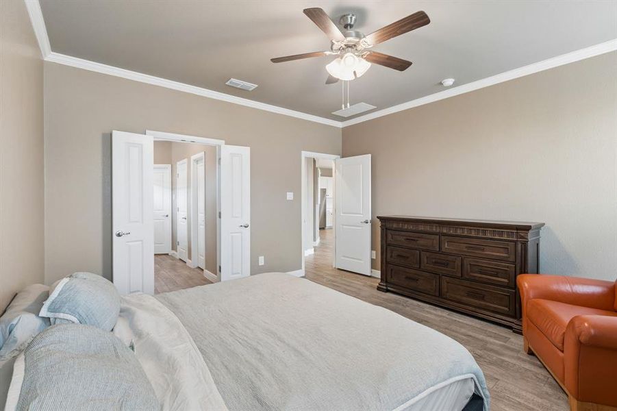 Spacious room featuring wood-finish flooring, neutral-toned walls, and white crown molding