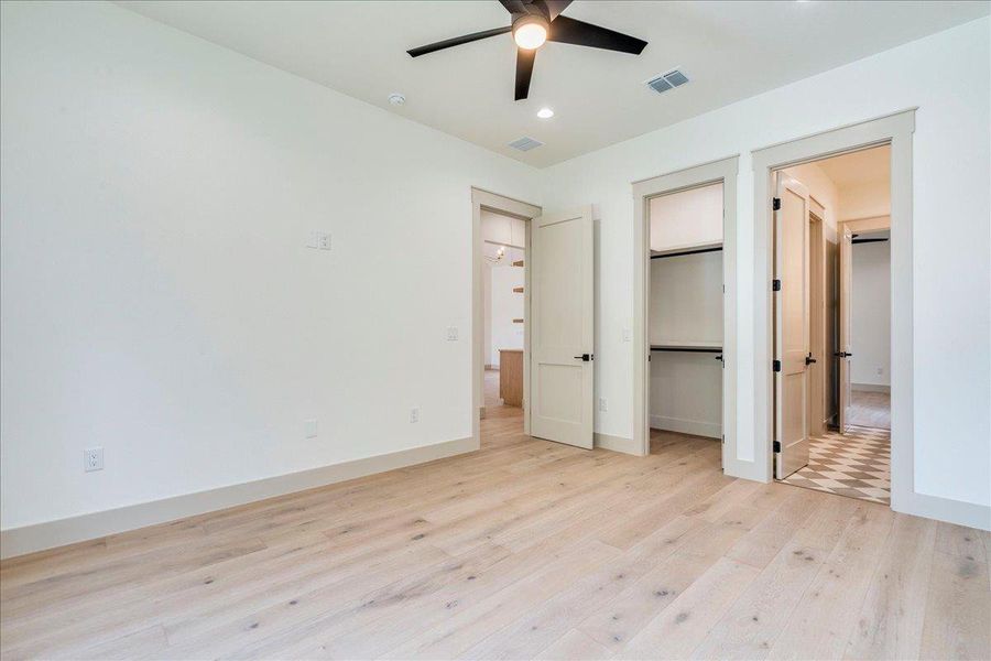 Blonde hardwood floors grace this naturally illuminated room, featuring two walk-in closets.