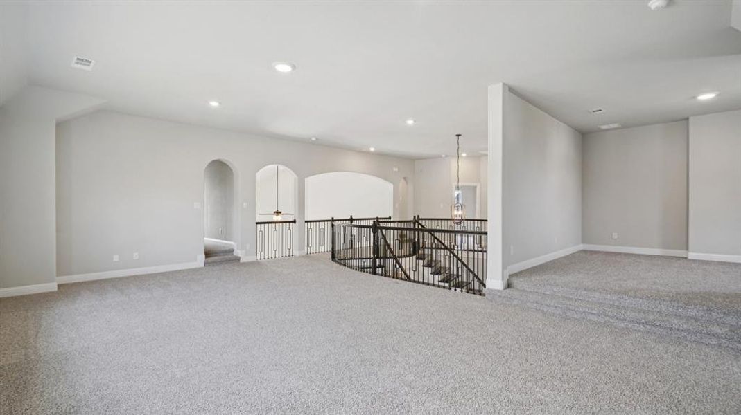 Unfurnished room featuring light colored carpet, recessed lighting, and arched walkways Unfurnished room featuring light colored carpet, recessed lighting, and arched walkways