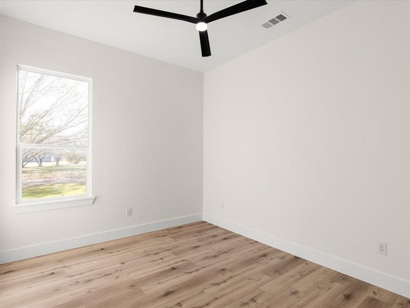 Room featuring wood-finish flooring, a contemporary ceiling fan, and crisp white baseboards
